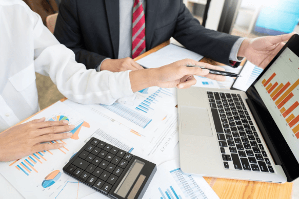 two people having a discussion in front of a laptop and financial statements
