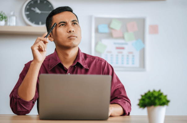 a man thinking while sitting in front of a laptop